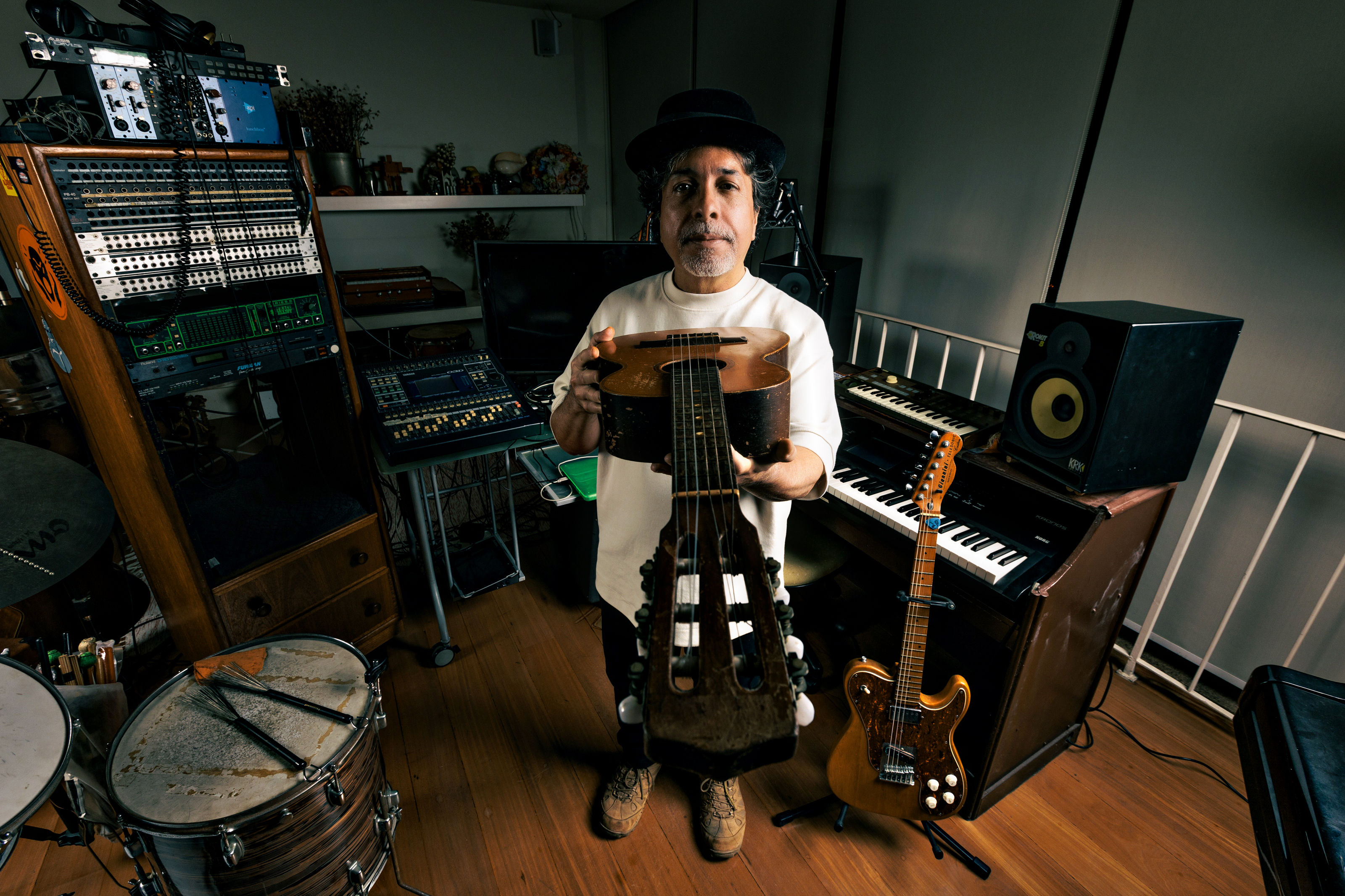 Marcelo Lobato, d’O Rappa, posando para uma foto em seu estúdio com um violão na mão.