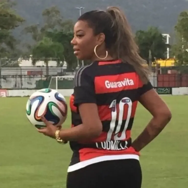 Cantora Ludmilla com a camiseta do Flamengo e bola de futebol na mão em campo
