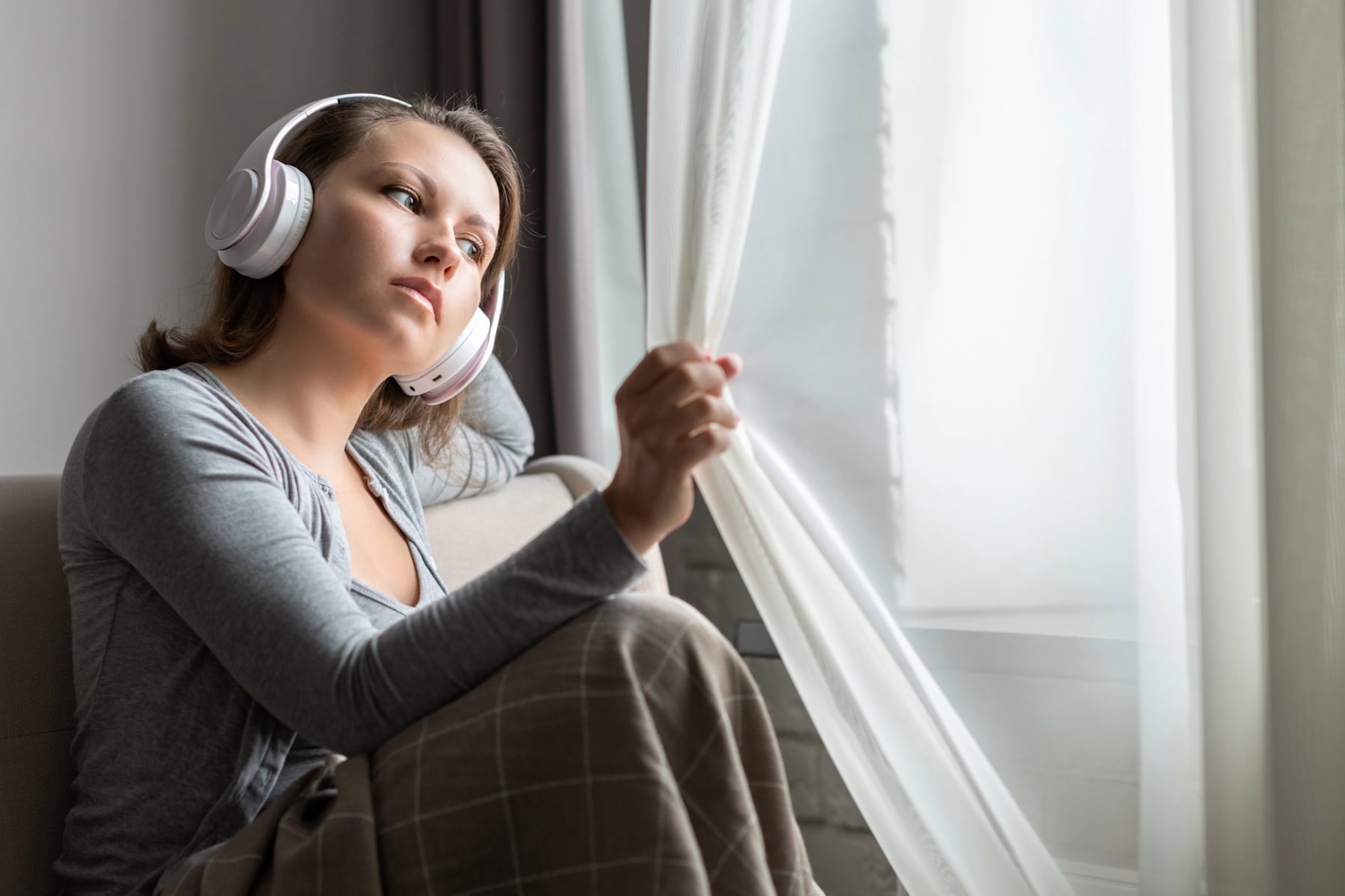 Mulher com semblante triste ouve música nos fones de ouvido